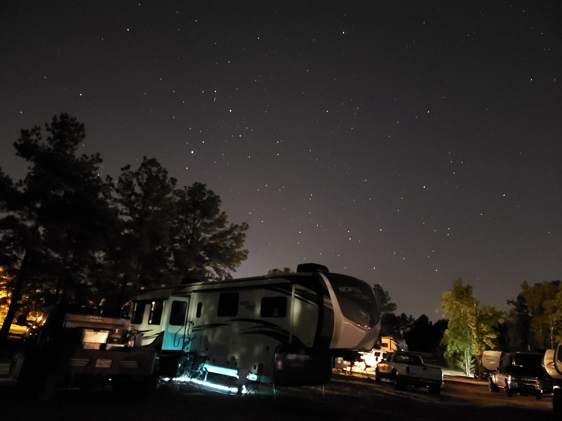 Camper lit up at night under pines